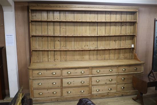 A large Victorian pine dresser, with three shelf rack and twelve long drawers, on plinth foot W.305cm H.243cm